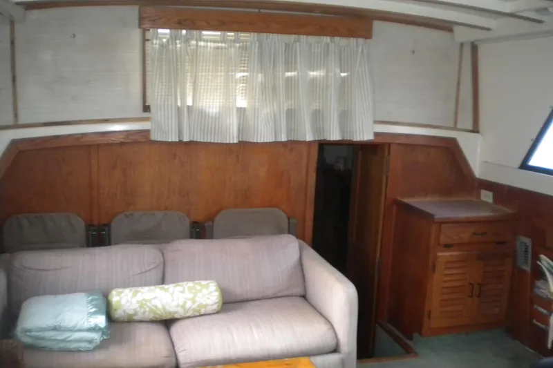 Slide: The Image of 1988 Mainship 40 Double Cabin interior with sofa, wooden cabinetry, and window curtains. - 41