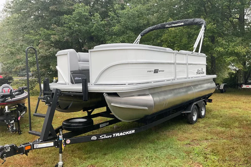 Slide: The Image of 2026 Sun Tracker PB 20 DLX pontoon boat on trailer, parked on grass. - 4
