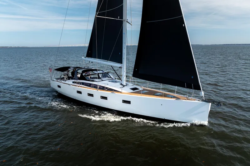 The Image of 2016 Jeanneau 64 sailing yacht with sleek black sails on open water. - 0