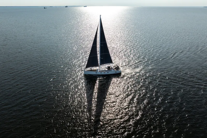 Slide: The Image of Sailing yacht Jeanneau 64 (2016) gliding on sunlit water, casting a long shadow. - 12