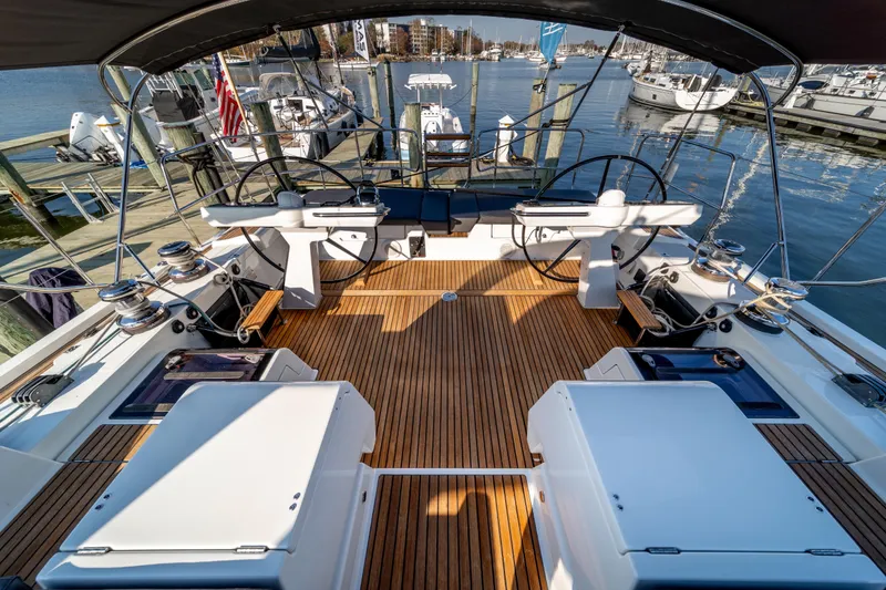 Slide: The Image of 2016 Jeanneau 64 yacht cockpit with dual steering wheels and teak decking at marina. - 19