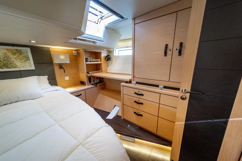 Slide: The Image of Luxurious 2016 Jeanneau 64 yacht cabin with modern wood furnishings and cozy bedding. - 36