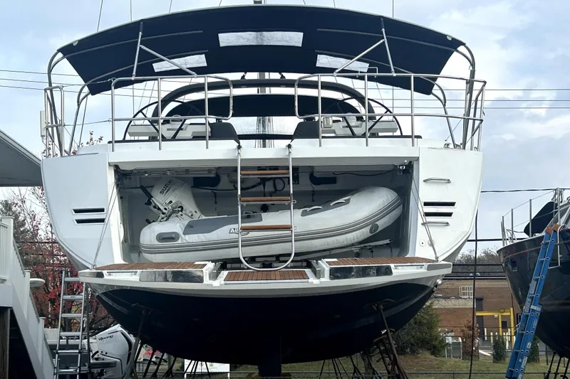Slide: The Image of 2016 Jeanneau 64 yacht with inflatable boat stored at the stern, docked outdoors. - 49