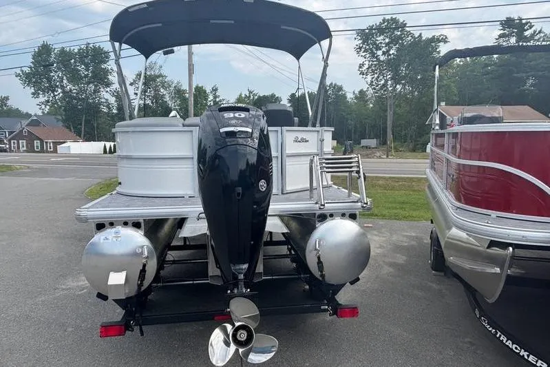 Slide: The Image of 2026 Sun Tracker PB 20 DLX pontoon boat with outboard motor, parked on a trailer. - 9