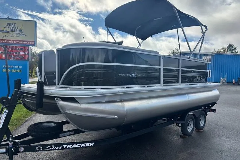 The Image of 2026 Sun Tracker Party Barge 20 DLX pontoon boat on trailer, parked outdoors. - 1