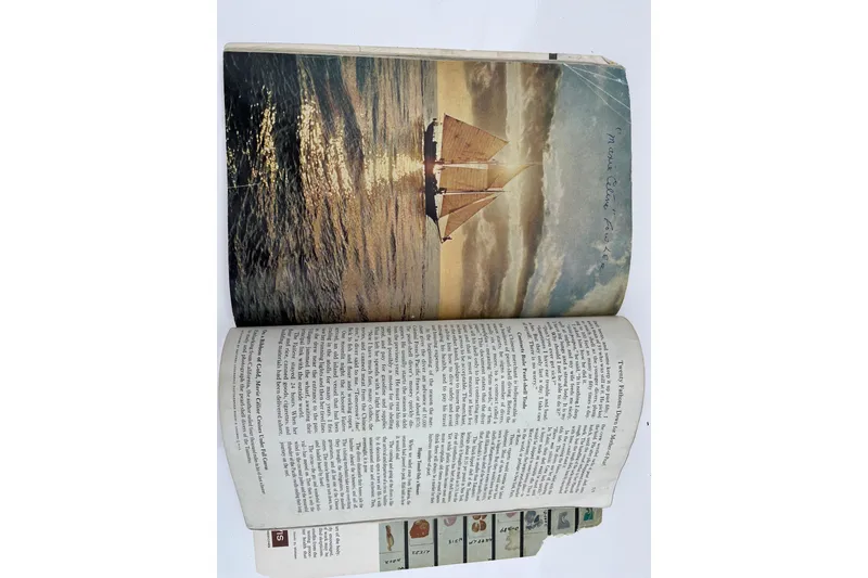 Slide: The Image of Open book showing a 1947 Murray Peterson Schooner sailing at sunset. - 142