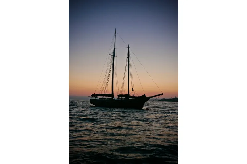 Slide: The Image of Silhouette of 1947 Peterson Schooner sailing at sunset on calm waters. - 144