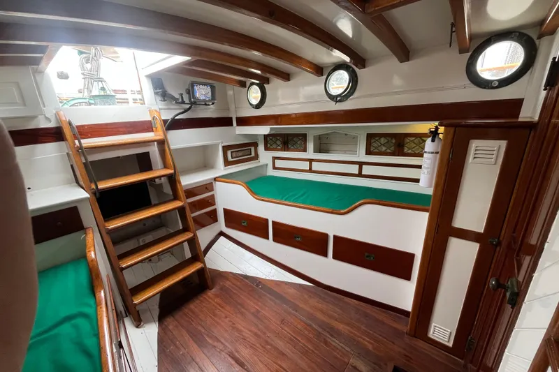 Slide: The Image of Interior of 1947 Murray Peterson Schooner with wooden finishes and green cushions. - 56