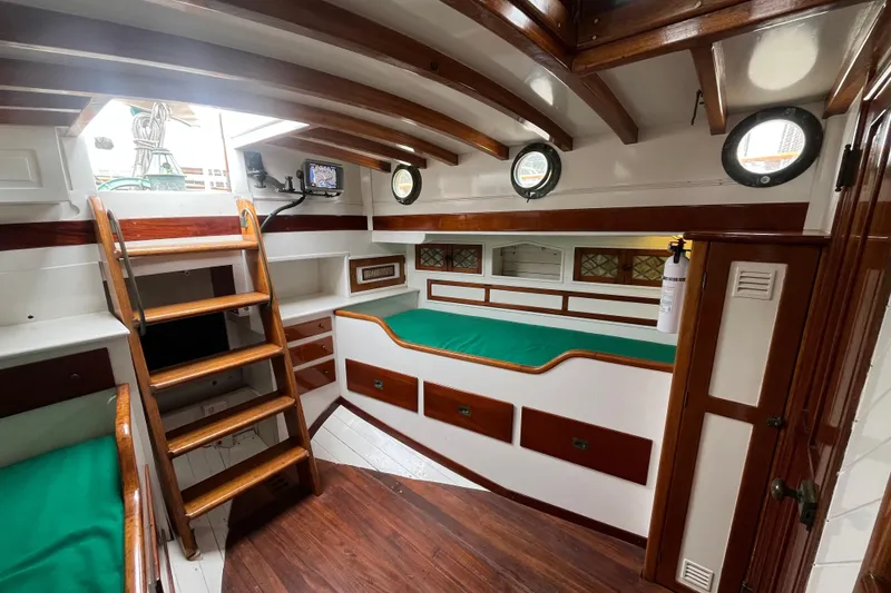 Slide: The Image of Interior of 1947 Murray Peterson Schooner with wooden finishes and green cushions. - 57