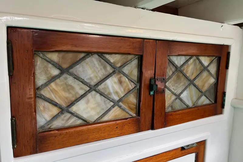 Slide: The Image of Wooden cabinet with stained glass doors on a 1947 Murray Peterson Schooner. - 62