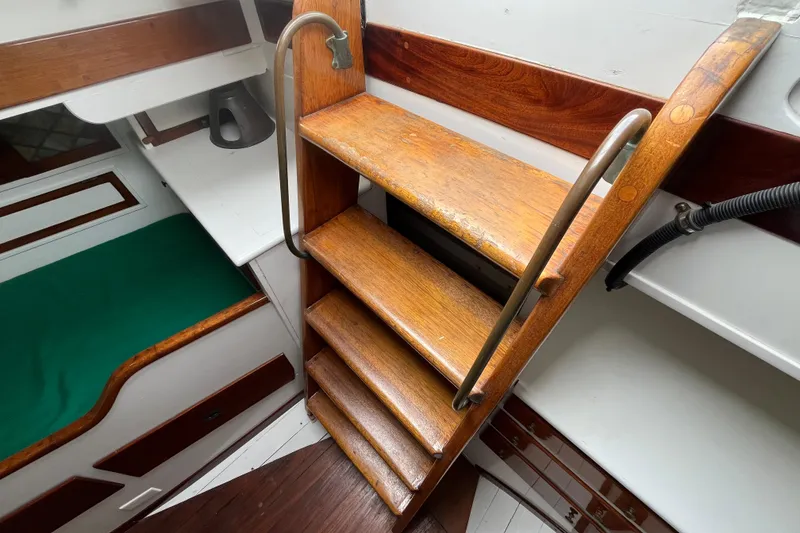 Slide: The Image of Wooden stairs inside 1947 Murray Peterson Schooner, featuring metal handrails and cabin interior. - 66