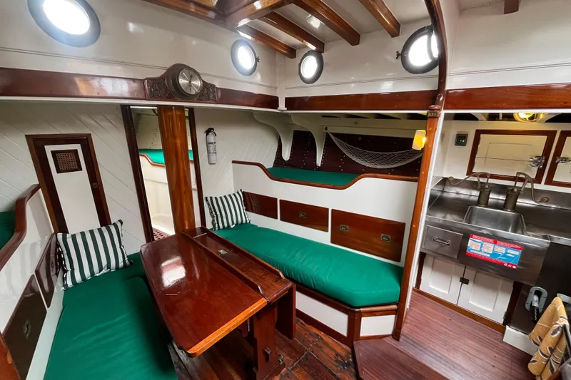 Slide: The Image of Interior of a 1947 Murray Peterson Schooner with wooden furnishings and green cushions. - 83