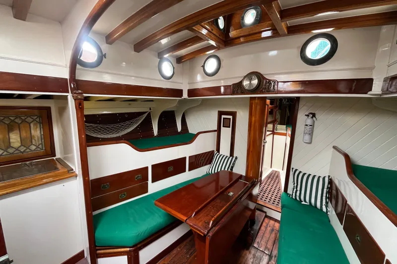 Slide: The Image of Interior of a 1947 Murray Peterson Schooner with green cushions and wooden accents. - 85