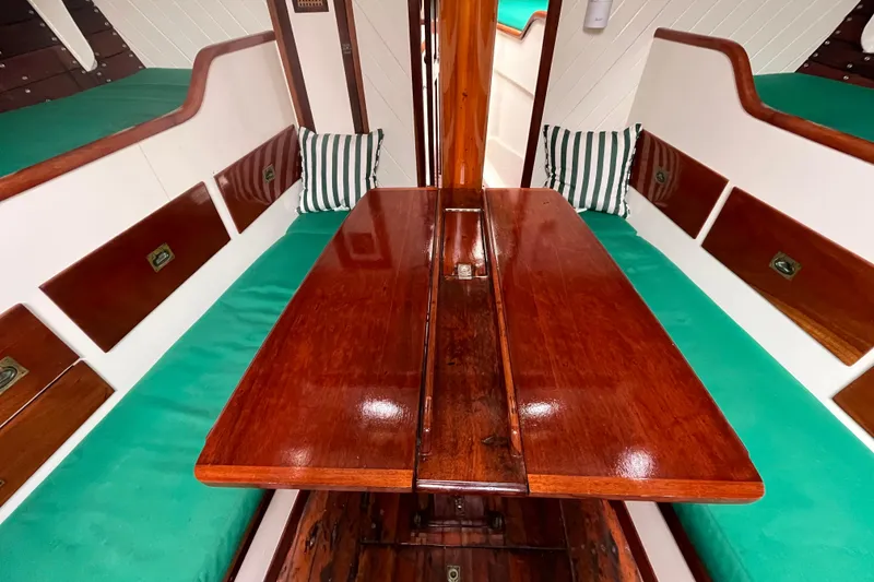 Slide: The Image of Interior of 1947 Murray Peterson Schooner with polished wood table and green cushioned seating. - 92