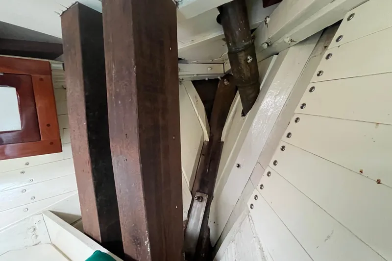 Slide: The Image of Interior view of 1947 Murray Peterson Schooner, showcasing wooden beams and metal pipe. - 99