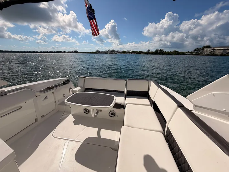 Slide: The Image of 2017 Monterey 378 Super Express boat interior with seating, table, and American flag on a sunny day. - 9