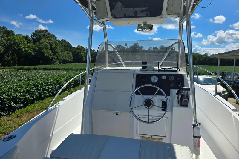 Slide: The Image of 1999 Sport-Craft 230 boat cockpit with steering wheel, dashboard, and clear sky background. - 10