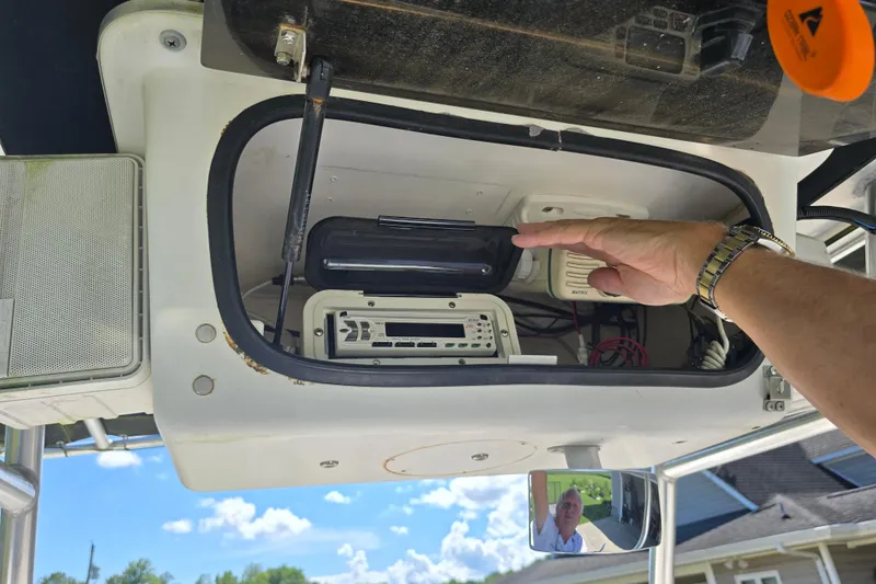 Slide: The Image of 1999 Sport-Craft 230 boat electronics compartment with hand adjusting equipment, clear sky background. - 15