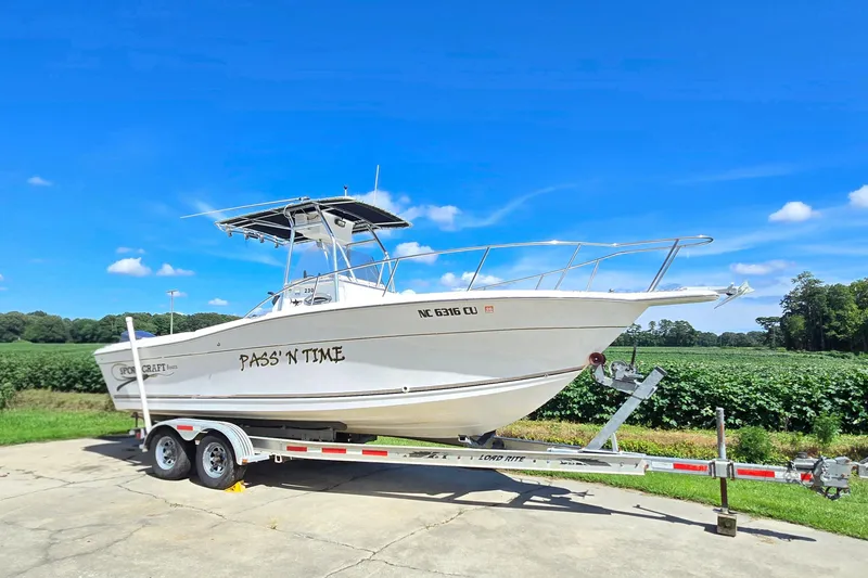 Slide: The Image of 1999 Sport-Craft 230 boat on trailer, "Pass'n Time," under clear blue sky. - 17