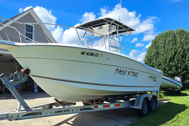 Slide: The Image of 1999 Sport-Craft 230 boat on trailer, parked near house under blue sky. - 3
