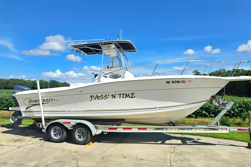 Slide: The Image of 1999 Sport-Craft 230 boat on trailer, named "Pass'n Time," under clear blue sky. - 4