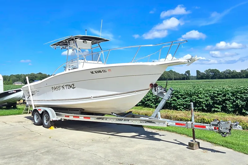 Slide: The Image of 1999 Sport-Craft 230 boat on trailer, parked outdoors under a clear blue sky. - 6