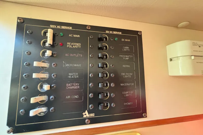 Slide: The Image of Electrical panel of a 2001 Albin 28 Tournament Express boat, showing AC and DC service switches. - 22