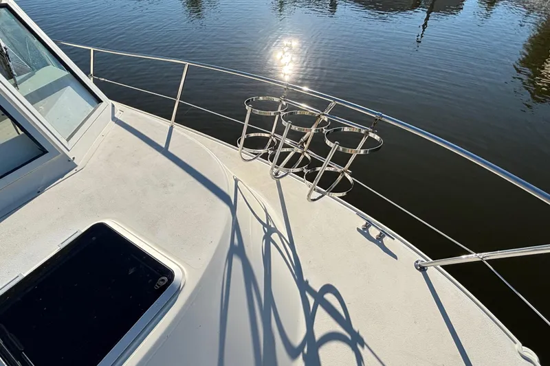 Slide: The Image of 2001 Albin 28 Tournament Express boat deck with rod holders, reflecting sunlight on water. - 7