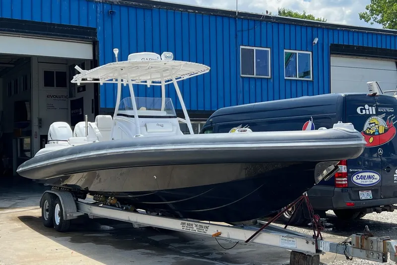 The Image of 2015 Airship 330 boat on trailer outside blue building, ready for transport. - 0