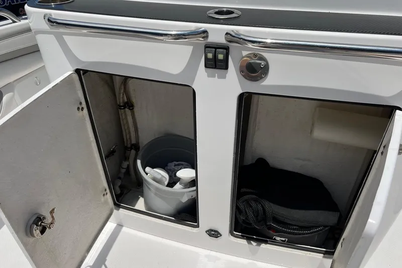 Slide: The Image of Open storage compartments on a 2015 Airship 330 boat, containing cleaning supplies and equipment. - 12
