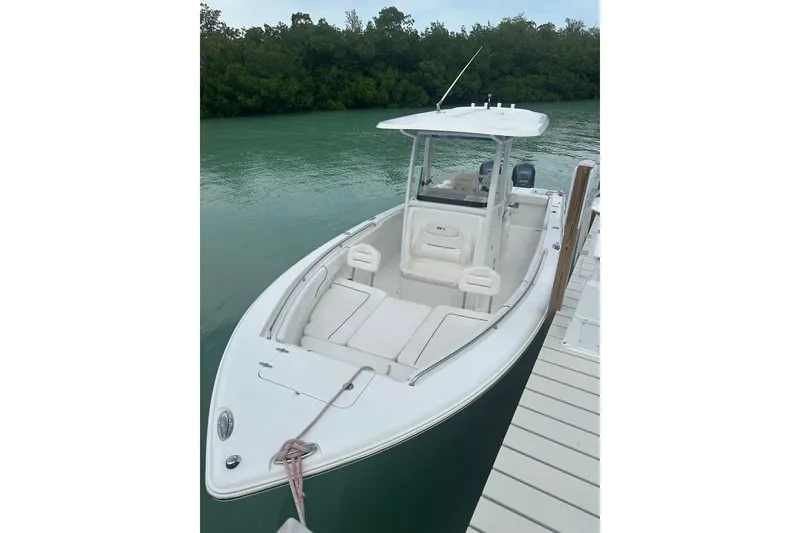 Slide: The Image of 2015 Sea Hunt Gamefish 25 boat docked by lush greenery. - 2