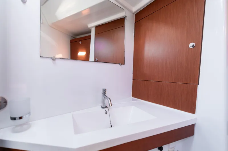 Slide: The Image of Modern bathroom interior on 2013 Beneteau Oceanis 50 yacht, featuring sleek sink and wooden cabinetry. - 19