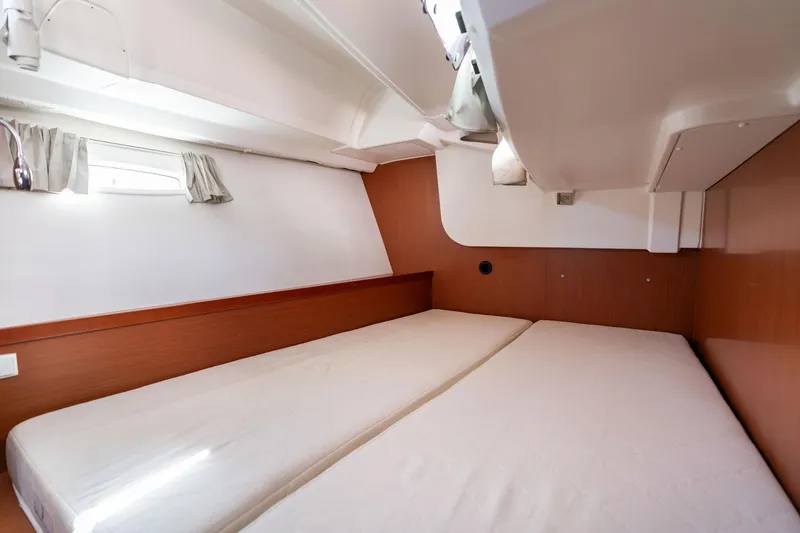 Slide: The Image of 2013 Beneteau Oceanis 50 cabin interior with twin beds and wooden paneling. - 24