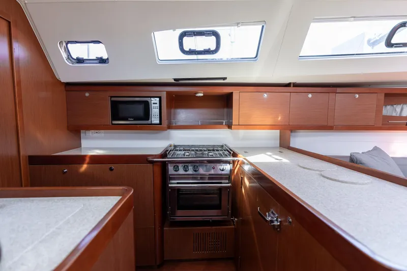 Slide: The Image of Interior of 2013 Beneteau Oceanis 50 yacht kitchen with stove, microwave, and wooden cabinetry. - 32