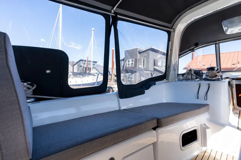 Slide: The Image of Interior view of 2013 Beneteau Oceanis 50 sailboat with cushioned seating and marina backdrop. - 53