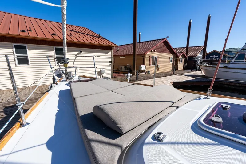 Slide: The Image of Beneteau Oceanis 50 sailboat deck with sunbathing area, docked near wooden buildings, 2013 model. - 62