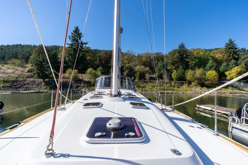 Slide: The Image of 2013 Beneteau Oceanis 50 sailboat on calm water, surrounded by lush greenery. - 63