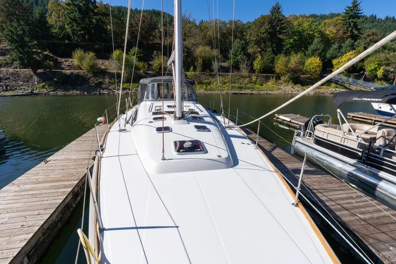 Slide: The Image of 2013 Beneteau Oceanis 50 sailboat docked on a serene lake with lush greenery. - 64