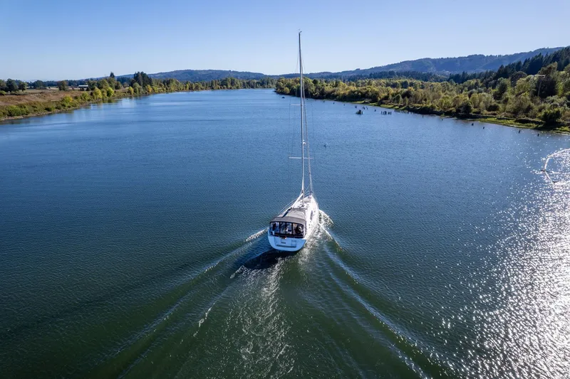 Slide: The Image of Sailboat Beneteau Oceanis 50 (2013) cruising on a scenic river under clear blue skies. - 66