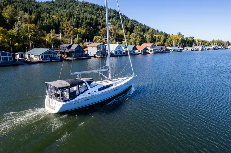Slide: The Image of Beneteau Oceanis 50 sailboat cruising near colorful waterfront homes, surrounded by lush greenery. - 68