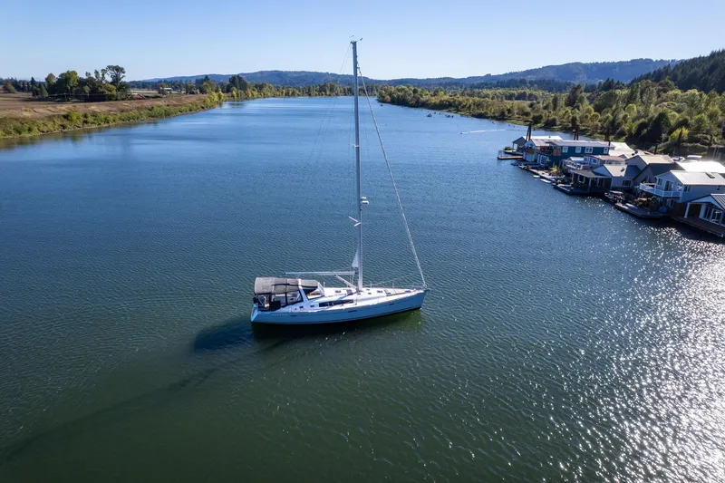 Slide: The Image of Beneteau Oceanis 50 sailboat on a serene river, surrounded by lush greenery and floating homes. - 72