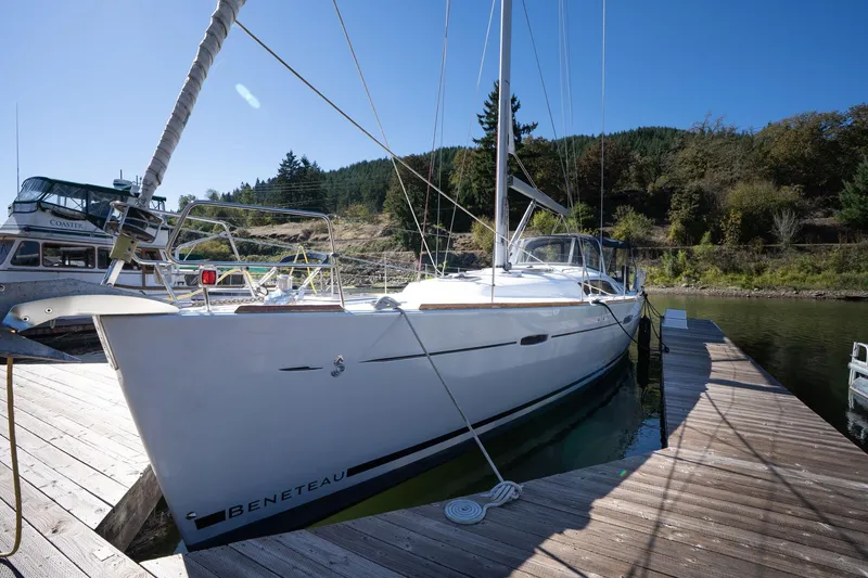 Slide: The Image of 2013 Beneteau Oceanis 50 sailboat docked at a marina, surrounded by lush greenery. - 82