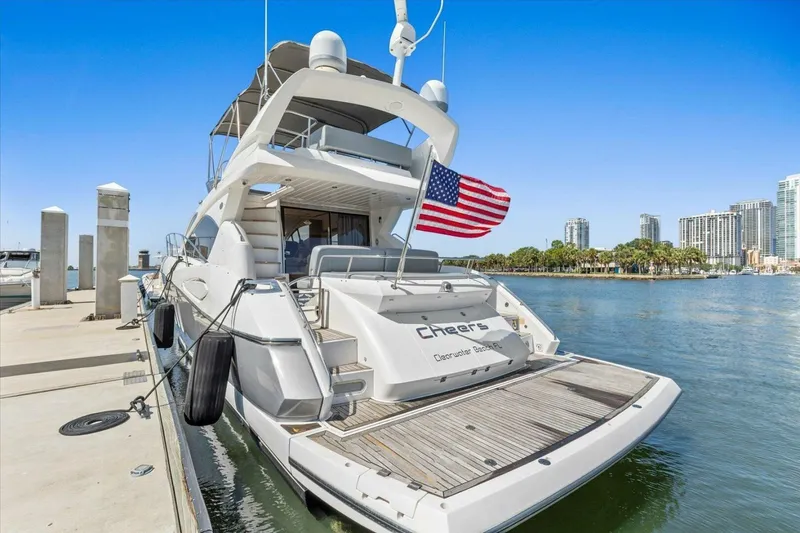 Slide: The Image of 2009 Sunseeker Manhattan 52 yacht docked, displaying an American flag, with city skyline backdrop. - 3