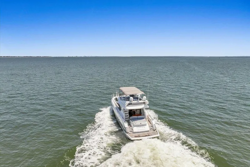 Slide: The Image of 2009 Sunseeker Manhattan 52 yacht cruising on open water under clear blue sky. - 60