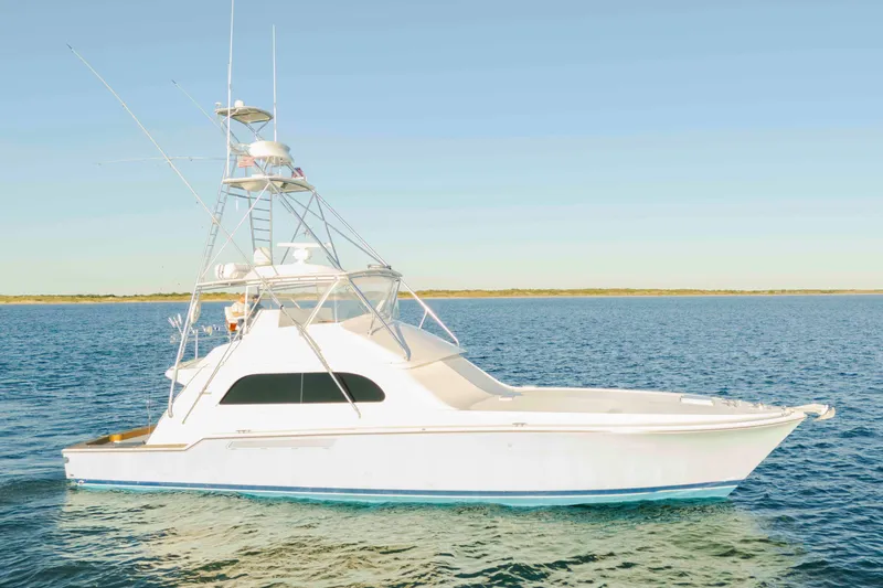 The Image of 1999 Bertram 60 Convertible yacht on calm blue waters under clear sky. - 0