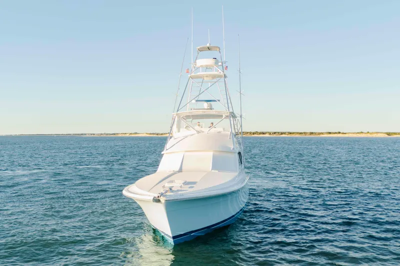 Slide: The Image of 1999 Bertram 60 Convertible yacht on open water, clear sky background. - 12