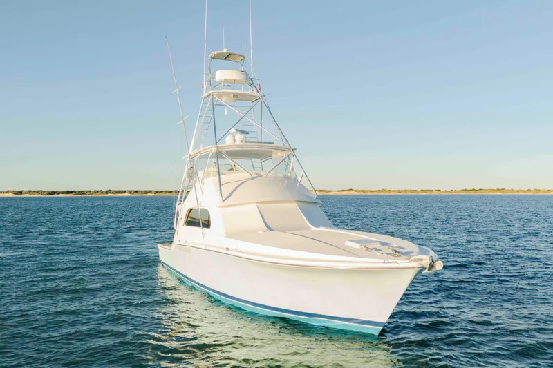 Slide: The Image of 1999 Bertram 60 Convertible yacht on calm blue waters under clear sky. - 14