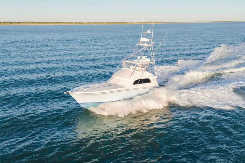 Slide: The Image of 1999 Bertram 60 Convertible yacht cruising on open water, creating a dynamic wake. - 26