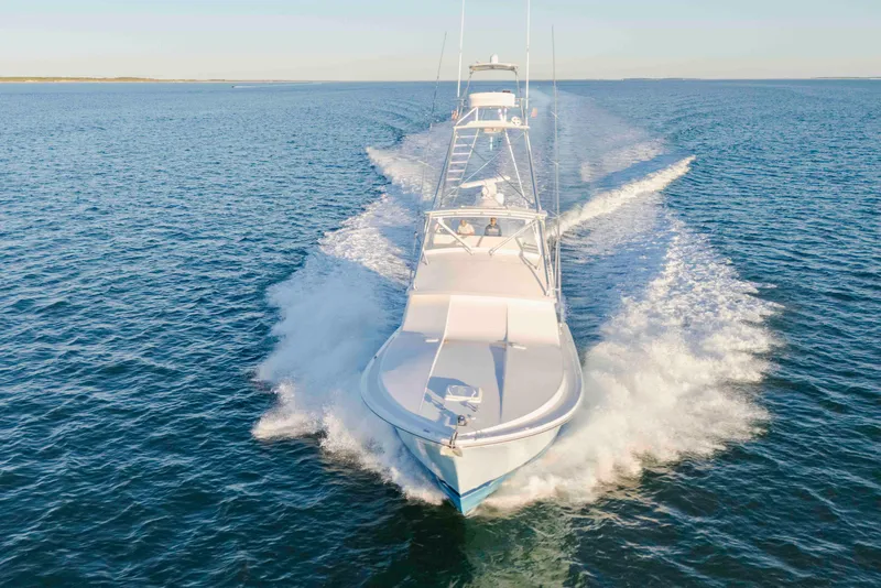 Slide: The Image of 1999 Bertram 60 Convertible yacht cruising on open water, creating a dynamic wake. - 28