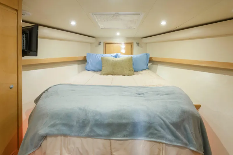 Slide: The Image of Cozy bedroom interior of 1999 Bertram 60 Convertible yacht with soft lighting and plush bedding. - 33